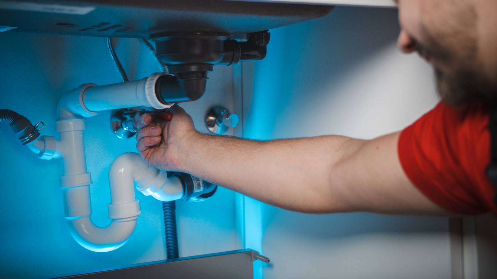 Plumber working on a burst pipe inside a wall
