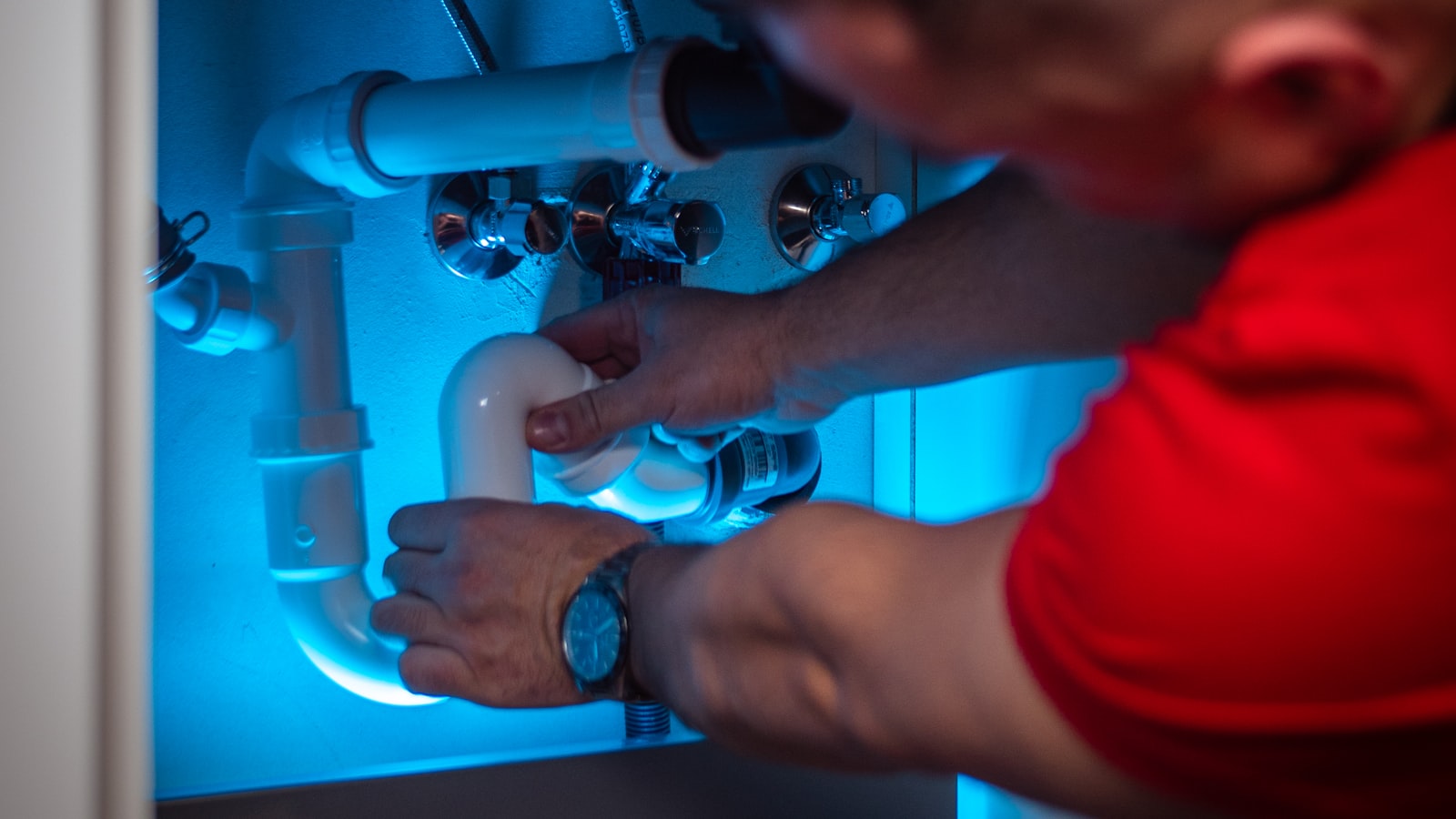 Northgate plumber working on pipework under a cabinet